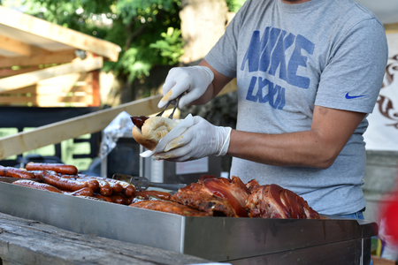 CLUJ NAPOCA, ROMANIA - JULY 8, 2016: Cook prepares a sausage hot dog in a fast food at the Street Food Festival of Clujのeditorial素材