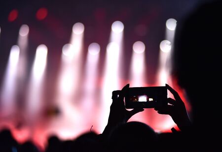 Close up of photographing stage lights with smartphone during a concert