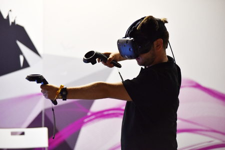 CLUJ-NAPOCA, ROMANIA - AUGUST 5, 2016: Boy tries virtual reality HTC Vive headset and hand controls during the virtual reality exposition, at the Untold Festivalのeditorial素材