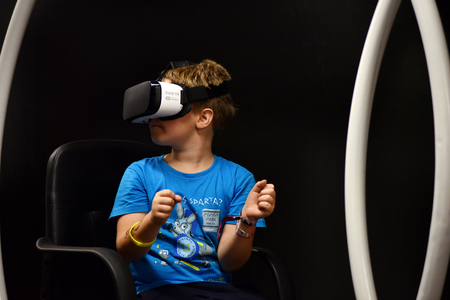 CLUJ-NAPOCA, ROMANIA - AUGUST 5, 2016: Boy tries virtual reality Samsung Gear VR headset and hand controls during the virtual reality exposition, at the Untold Festivalのeditorial素材