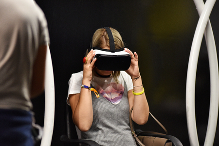 CLUJ-NAPOCA, ROMANIA - AUGUST 7, 2016: Girl tries virtual reality Samsung Gear VR headset and hand controls during the virtual reality exposition, at the Untold Festivalのeditorial素材