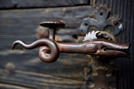 Ornamental vintage iron door handle on a wooden door