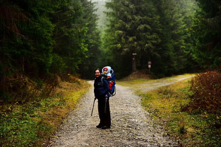 Young mother trekking, carrying her baby in a baby backpack child carrierの写真素材