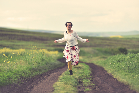 Woman in white skirt running on a countryside road. Freedom conceptの写真素材