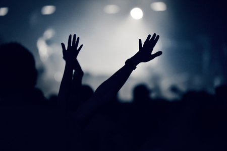 Crowd at a music concert with raising hands up, toned imageの写真素材