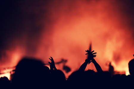 Silhouette of hands on a concert in front of bright stage lights