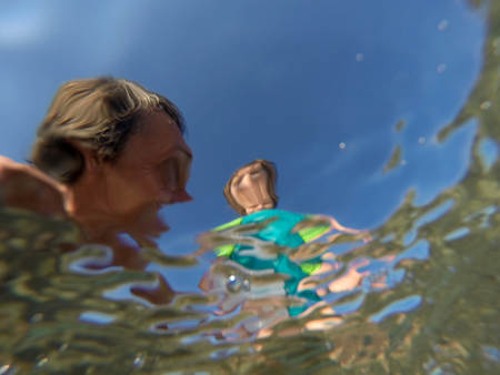 Father and her toddler daughter having fun at the sea. Distorted faces view through water, underwater viewの写真素材