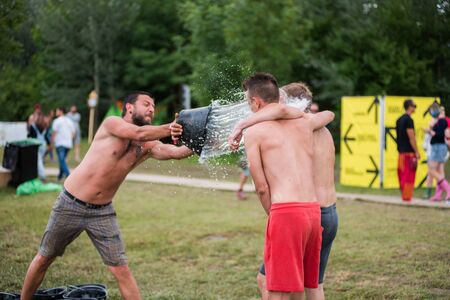 BONTIDA, ROMANIA - JULY 16, 2017: Funny guy spours water from a bucket on his friend head at Electric Castle Festivalのeditorial素材