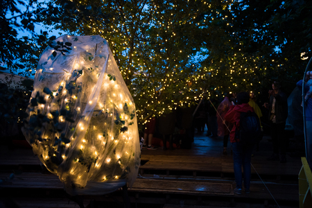 BONTIDA, ROMANIA - JULY 15, 2017: People relaxing in a special chilling natural area decorated with small led lamps at Electric Castle festivalのeditorial素材