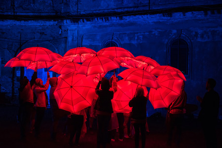 BONTIDA, ROMANIA - JULY 15, 2017: People playing with colorful red umbrellas illuminated by led lamps during night at Electric Castle festivalのeditorial素材