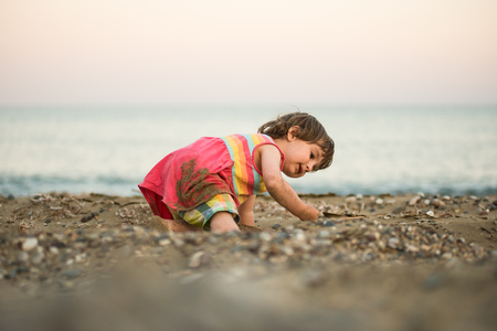 Adorable toddler baby playing on a beach with pebble stones.のeditorial素材