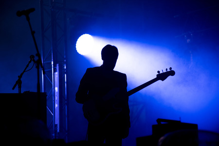Silhouette of a guitar player on the stage. Smoke and stage lightsの写真素材