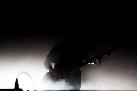 Silhouette of a guitar player on the stage. Smoke and stage lightsの写真素材