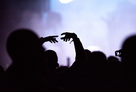 Rear view of silhouette of crowd with arms outstretched at concert. Summer music festival conceptの写真素材