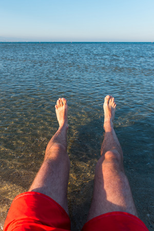 Sea waves washing man's feet. Man relaxing on the beachの写真素材