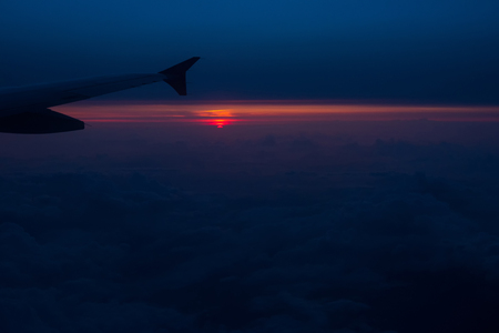 Sunset view from an airplane. Flying over the clouds in colorful sunsetの写真素材