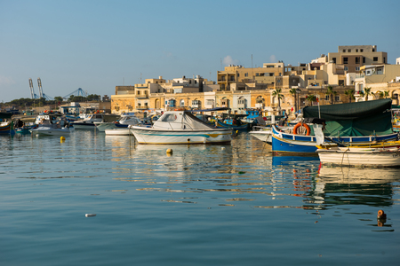 MARSAXLOKK, MALTA - AUGUST 23, 2017: Traditional colorful luzzu fishing boats arriving and anchoring early in the morning in Marsaxlokk village harborのeditorial素材