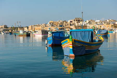 MARSAXLOKK, MALTA - AUGUST 23, 2017: Traditional colorful luzzu fishing boats arriving and anchoring...
