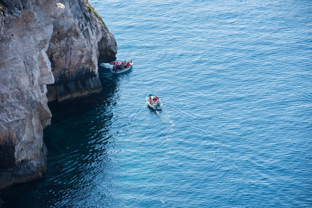 BLUE GROTTO, MALTA - AUGUST 23, 2017: Tourists taking a boat trip at the Blue Grotto. The sea caves of Blue Grotto and natural arch are one of the major tourist sights of Maltaのeditorial素材