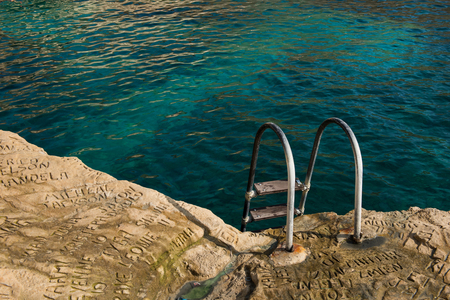 SAINT PETER'S POOL, MALTA - AUGUST 21, 2017: People carving and engraving their names and initials in the rocks at Saint Peter's pool, a natural swimming pool with crystal clear blue-green watersのeditorial素材