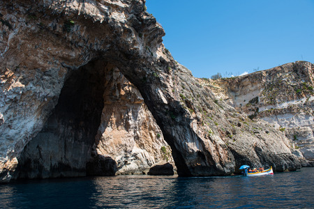 BLUE GROTTO, MALTA - AUGUST 23, 2017: Tourists taking a boat trip at the Blue Grotto. The sea caves of Blue Grotto and natural arch are one of the major tourist sights of Maltaのeditorial素材
