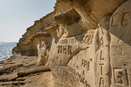SAINT PETER'S POOL, MALTA - AUGUST 21, 2017: People carving and engraving their names and initials in the rocks at Saint Peter's pool, a natural swimming pool with crystal clear blue-green watersのeditorial素材