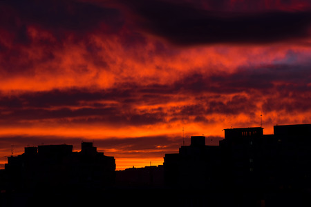 Sunrise in the city. Silhouette of residential apartments, flat of blocks against vibrant red skyの写真素材