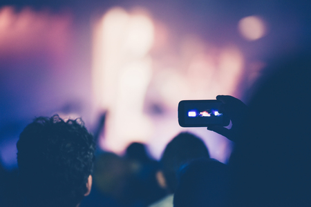 Fan taking photo of concert at festival with a mobile phoneの写真素材