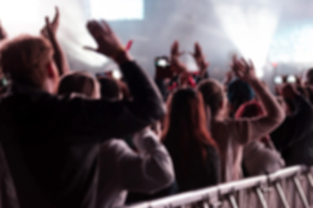 Blurred background with crowd of people partying and stage lights at a live concert