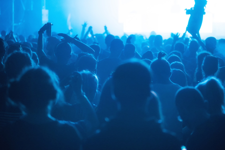 Crowd of cheerful people partying at music festival. Rear view, stage concert lightsの写真素材