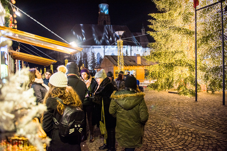 CLUJ NAPOCA, ROMANIA - DECEMBER 30, 2017: Cheerful people enjoying the Christmas market at night in the center of the old city and buying presents and goodiesのeditorial素材