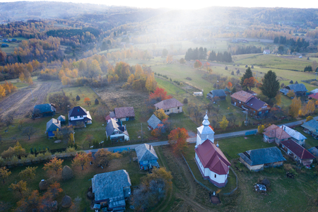 Aerial top drone view of countryside village in Transylvania, Romania. Sunset over orthodox churchの写真素材