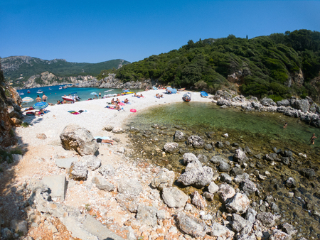 LIMNI, CORFU, GREECE - AUGUST 29, 2018: Tourists sunbathing in summer vacation on the beachのeditorial素材
