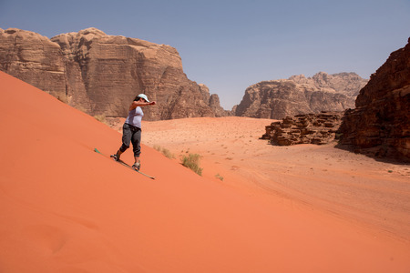 WADI RUM, JORDAN - MAY 18, 2018: Girl sandboarding on the red sand dunes of the desertのeditorial素材