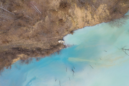 Aerial drone view of a boat in a turquoise lake contaminated with cyanide mining residuals