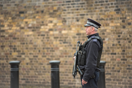 LONDON, UK - MARCH 22, 2019: Armed British police officer on duty patrolling and preventing terrorism attacks on the streets of the cityのeditorial素材