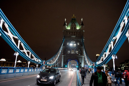 LONDON, UK - MARCH 22, 2019: Tourists walking on the illuminated Tower Bridge over the Thames river at nightのeditorial素材