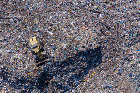 Aerial top drone view of large garbage pile, trash dump, landfill, waste from household dumping site, excavator machine is working on a mountain of garbage. Consumerism and contamination conceptの写真素材