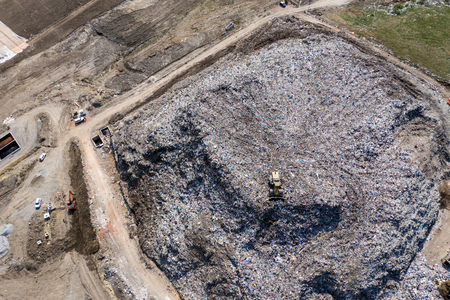 Aerial top drone view of large garbage pile, trash dump, landfill, waste from household dumping site, excavator machine is working on a mountain of garbage. Consumerism and contamination conceptの写真素材