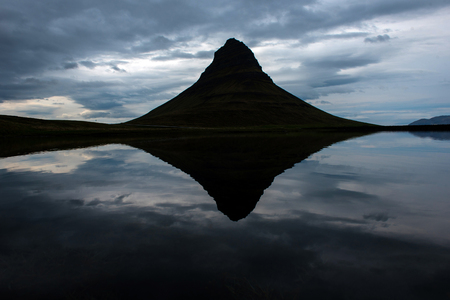 Reflection of the Kirkjufell mountain, one of Iceland iconic tourisitic destinations, in dark, sunset light. Snaefellsnes peninsula, Icelandの写真素材
