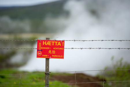 Warning danger sign in different languages near a boiling geothermal hot spring in Icelandの写真素材
