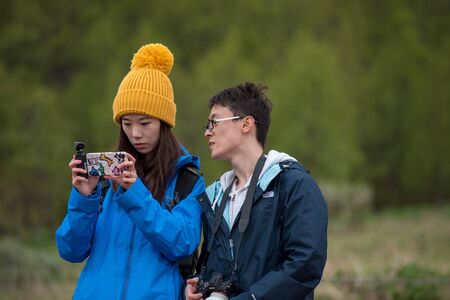 STROKKUR GEYSER, ICELAND - MAY 20, 2019: Asian tourists photographing the Strokkur geyser with a smart phone while erupting in the Golden Circleのeditorial素材