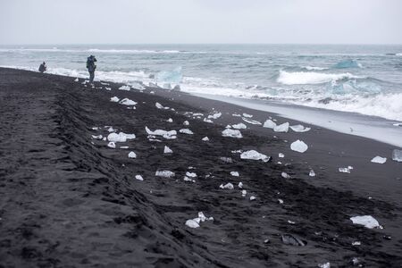 DIAMOND BEACH, JOKULSARLON, ICELAND - MAY 22, 2019: Tourists admiring and photographing the melting icebergs on the Atlantic ocean coast in Jokulsarlonのeditorial素材