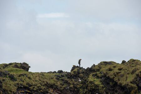 LONDRANGAR, ICELAND - MAY 19, 2019: Tourist posing on the top of the Londrangar basalt cliffs in the Snaefellsnes paninsula, Icelandのeditorial素材