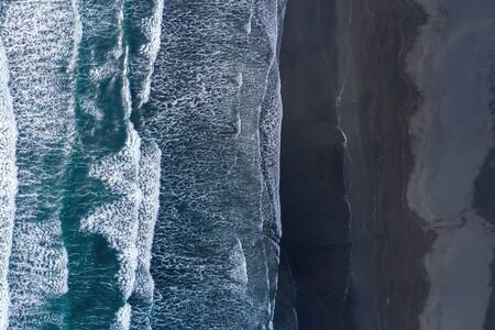 Aerial drone view of ocean waves washing black basaltic sand beach, Iceland
