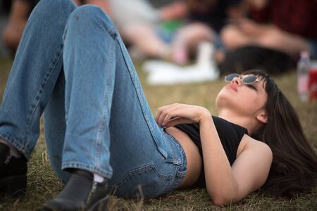 BONTIDA, ROMANIA - JULY 19, 2019: Party girl relaxing and laying down on the grass during a concert at Electric Castle Music Festivalのeditorial素材