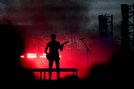 Silhouette of a guitarist in red stage lightsの写真素材