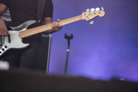 Detail of a musician playing on a bass guitar at concert