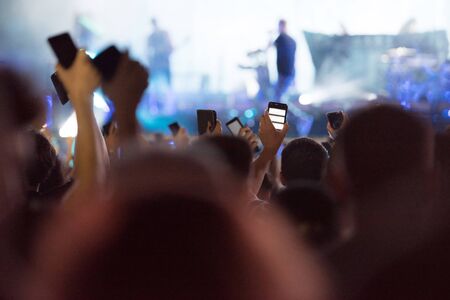 People taking photographs with smart phones during a music concert