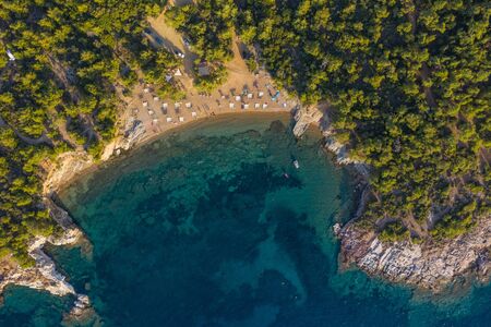 Aerial drone view of beach umbrellas and sunbeds on the coast in Thassos island, Greece